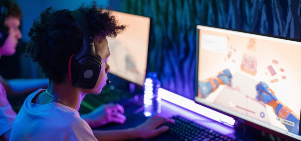 Boy with headphones playing video games on a computer